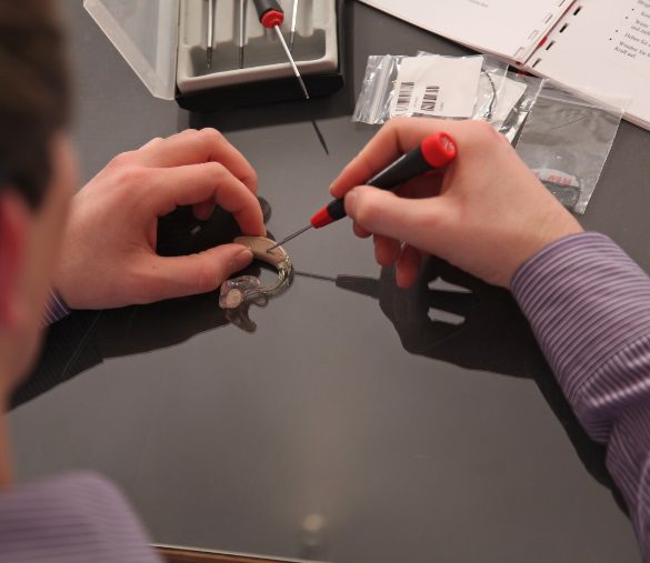 Hometown Hearing Centre's hearing aid repair specialist opening a hearing device