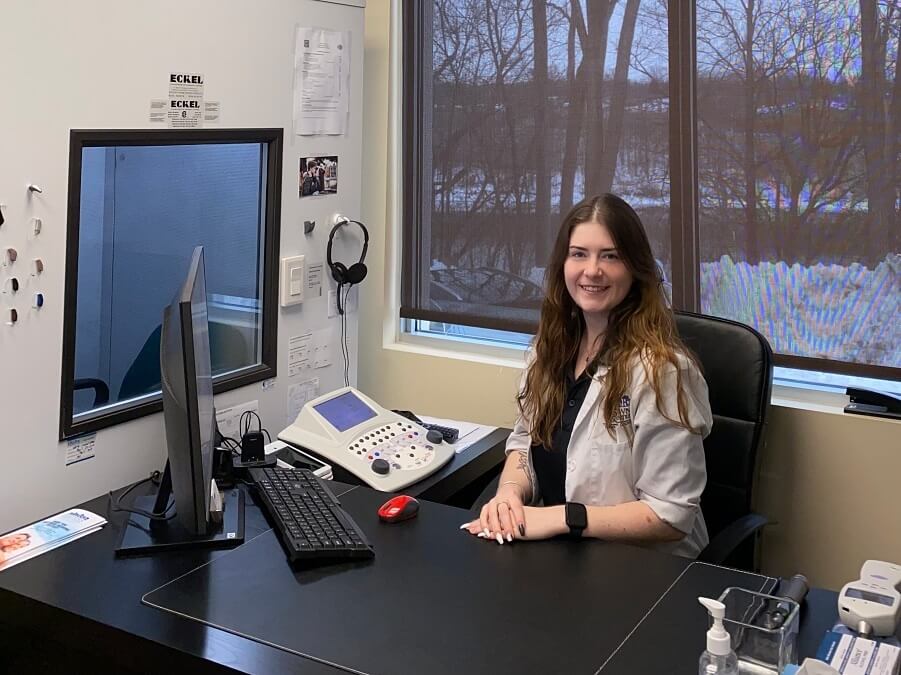 Hearing instrument specialist sitting with tinnitus testing equipment nearby